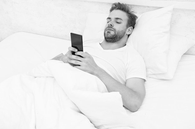 Morning vibes whole world in phone he is blogging flirting and sending text message internet addiction and mobile abuse concept man in bed chatting man use smartphone from the early morning