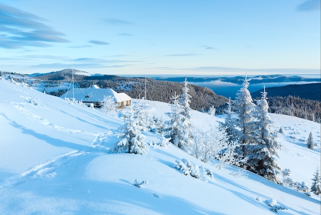 Morning winter mountain landscape with house on ridge and footsteps