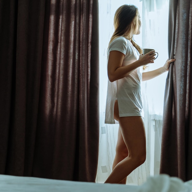 Morning woman wake up extend curtains to let sun into room