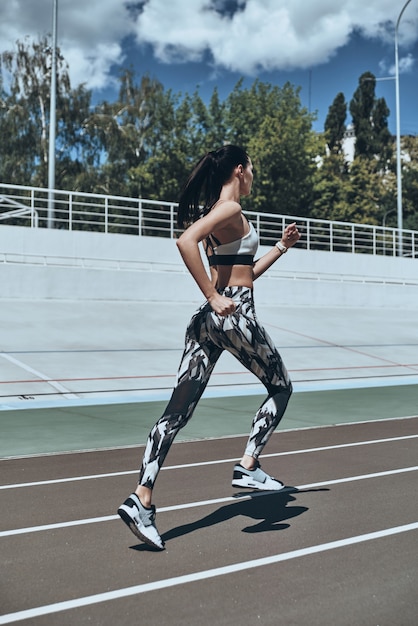 Morning workout. Full length of young woman in sports clothing jogging while exercising outdoors