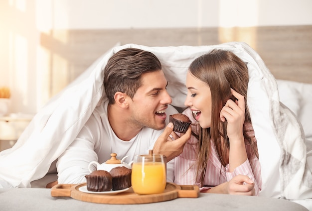 Morning of young couple having breakfast in bed