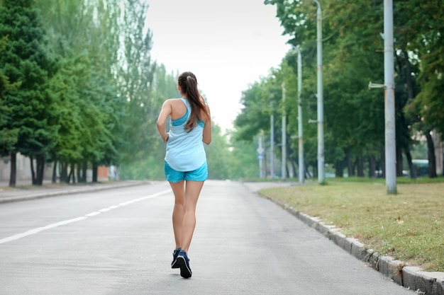 屋外で走っている若いスポーティな女性の朝