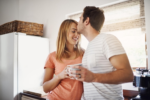 Mornings made with love Shot van een aanhankelijk jong stel dat 's ochtends thuis samen van koffie geniet