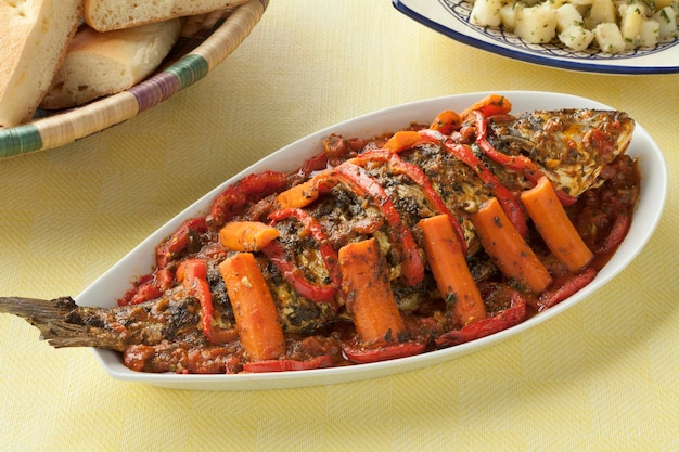 Foto tagine di pesce marocchino con pane di chermoula e insalata