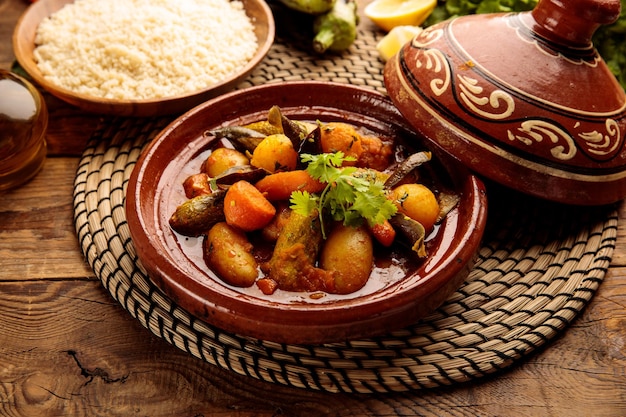 Марокканский таджин с рисом подается в блюде, изолированном на деревянном фоне, вид сбоку