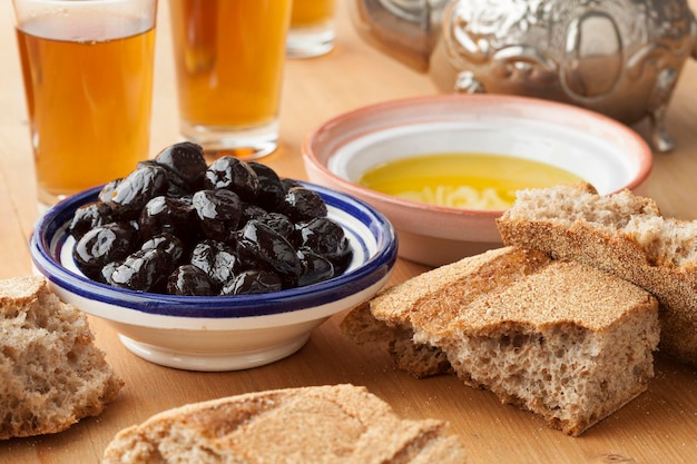 Moroccan traditional breakfast with olive oil black olives bread and tea on the table close up