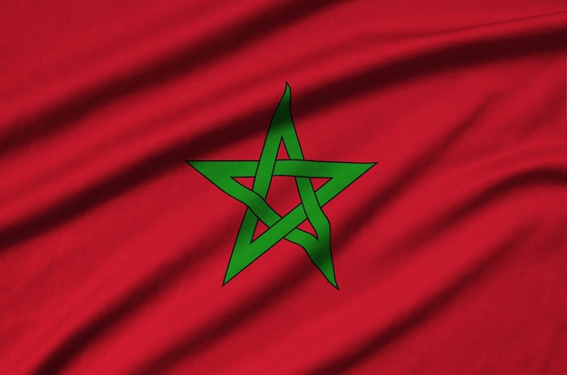 Morocco flag is depicted on a sports cloth fabric with many folds.