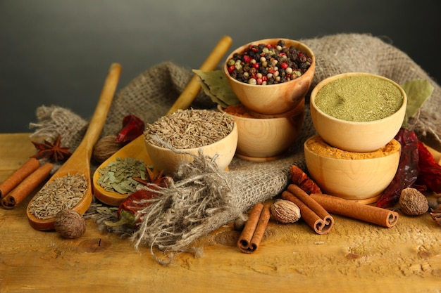 Mortar bowls and spoons with spices on table on grey background