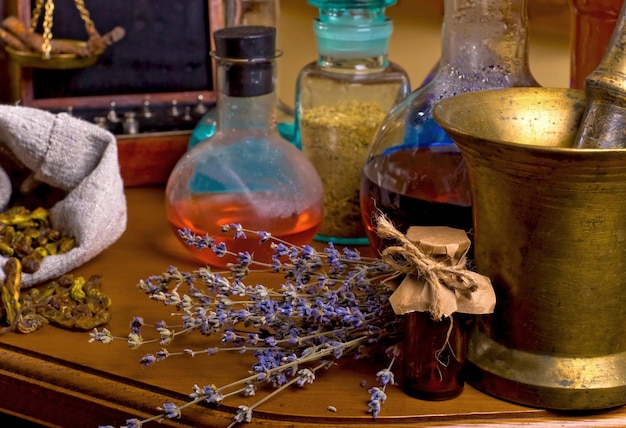 Ступка и пестик рядом с зельями на деревянном столе Сушеные целебные травы, цветы и ритуал свечей