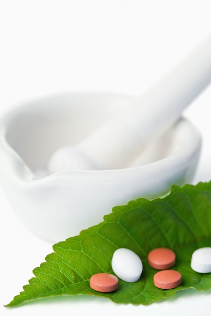 Mortar and pestle with pills on a leaf