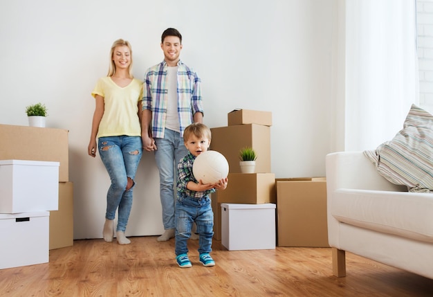 mortgage, people, housing, moving and real estate concept - happy family with boxes playing ball at new home