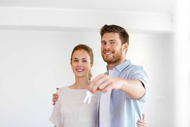 Mortgage people and real estate concept happy couple with keys at empty room of new home