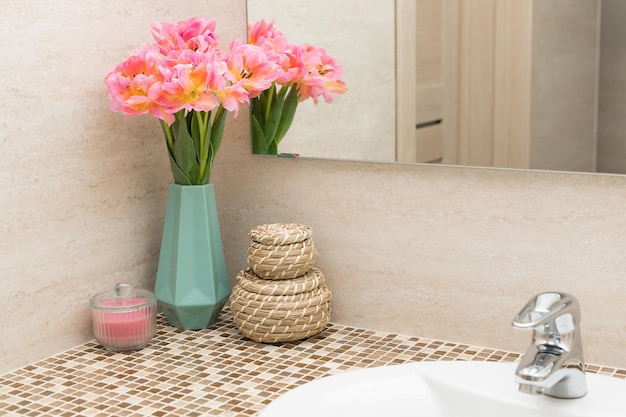 Controsoffitto bagno in mosaico con lavabo bianco fiori di tulipano e cesto