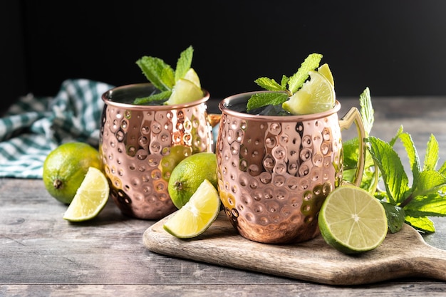 Moscow mule cocktail served with ice and lime slice on wooden table