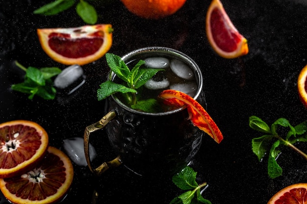 Moscow mule cocktail splashing in copper cup with blood orange\
ginger beer vodka and mint banner menu recipe place for text