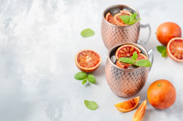 Moscow mule cocktail with fresh mint leaves and ice in copper mugs