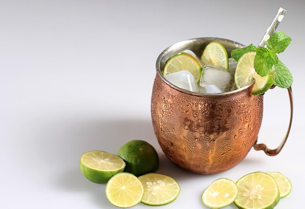 Moscow Mule Ice Cold Cocktail in Copper Cup with Lime and and Mint White Table Background