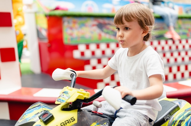 Moscow, russia, 28 may 2021 - little happy kid boy fun riding\
an small electric cars on sport ground in a playground for\
entertainments. children riding in the toy auto in an amusement\
park