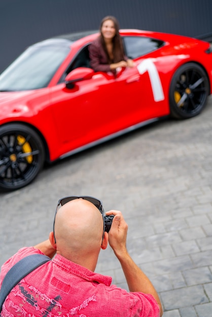 Foto mosca. russia. 13 agosto 2021 fotografo e macchina rossa. sessione fotografica professionale di un'auto rossa. il fotografo tiene la macchina fotografica in mano.