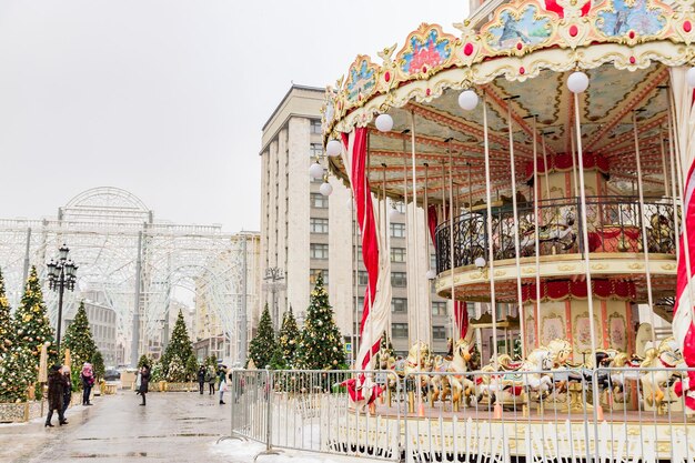 写真 moscow russia december 20 christmas decorated trees and colorful carousel in manezhnaya square in a snowy day