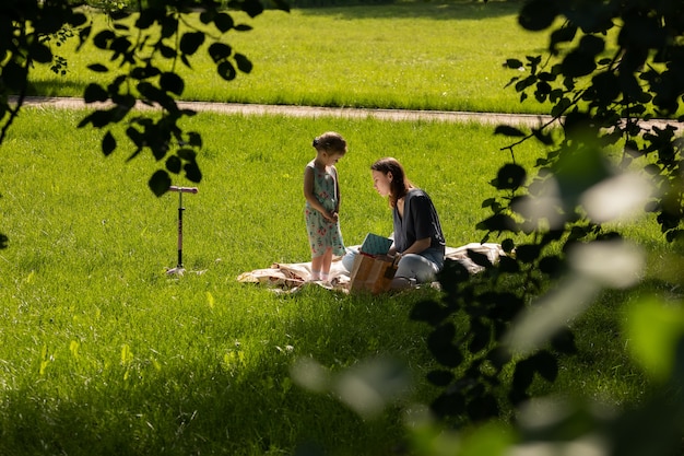 Moscow/Russia - June 2020: mother and daughter sitting on the grass and reading book