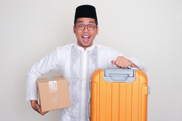 Moslem Asian man showing funny wow expression while carrying suitcase and package box