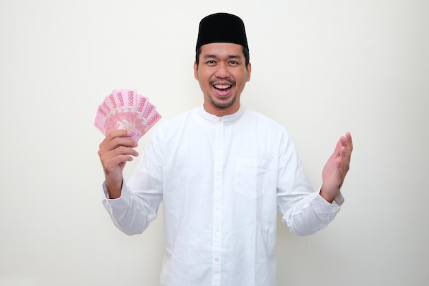 Мужчина-мусульманин Азии показывает счастливое выражение лица, держа деньги