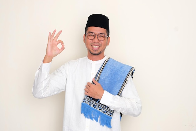 Moslem Asian man smiling happy and give OK finger sign at the camera