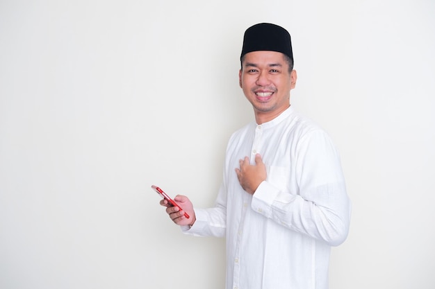 Moslem Asian man smiling happy while holding mobile phone