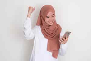 Photo moslem asian woman showing excited when looking to mobile phone that she hold