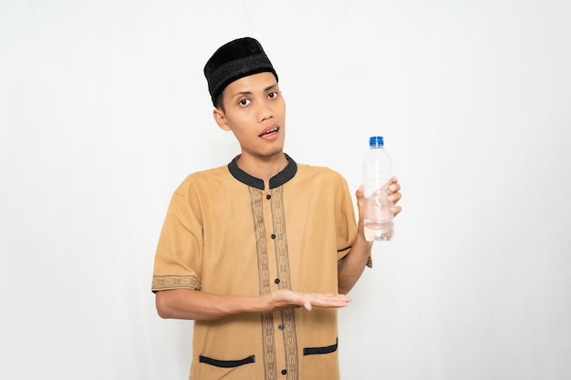 Foto moslim aziatische man draagt islamitische kleding met mineraalwater in een fles geïsoleerde witte achtergrond