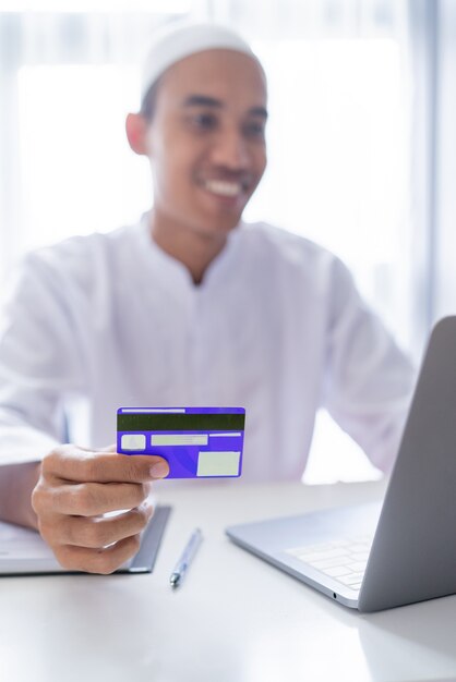 Moslim Aziatische man met behulp van creditcard voor betalingstransactie in de online winkel