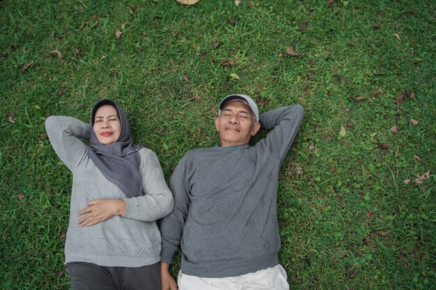 Moslim hogere man en vrouw die op gras leggen