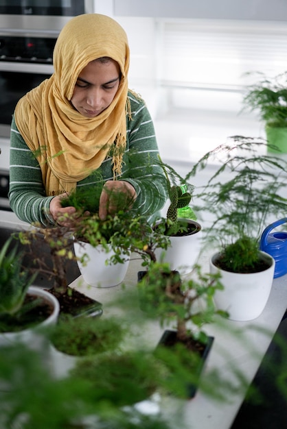 Moslim huisvrouw thuis planten in de keuken water geven