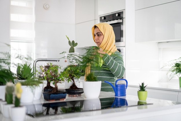 Moslim huisvrouw thuis planten in de keuken water geven