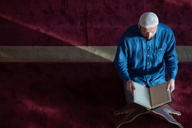 Foto moslim man bidt allah alleen in de moskee en leest het islamitische hulstboek koran bovenaanzicht