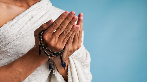 Moslim man in ihram kleding bidt met gebedskralen in zijn handen