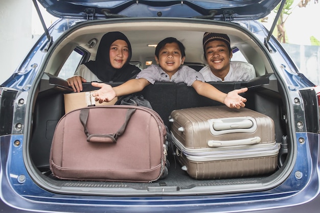 Moslim ouder en kind kijken naar de achterkant van de kofferbak vol met koffer klaar om op vakantie te gaan.