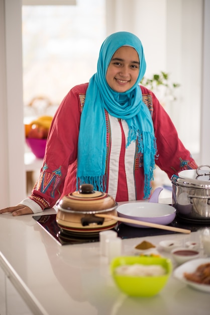 Moslim traditioneel jong meisje die voedsel in keuken maken