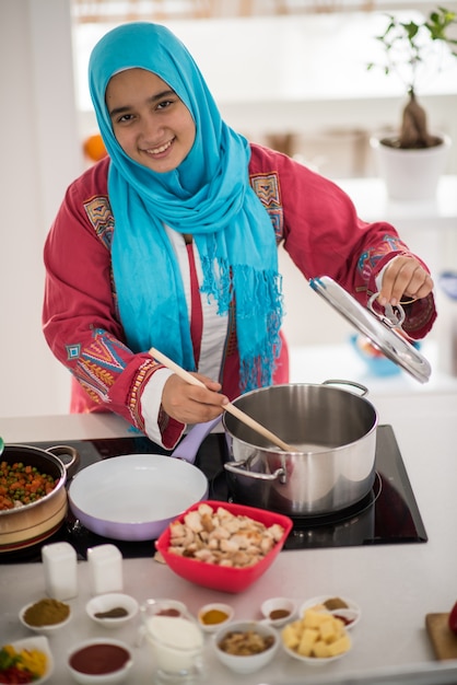 Moslim traditioneel jong meisje die voedsel in keuken maken