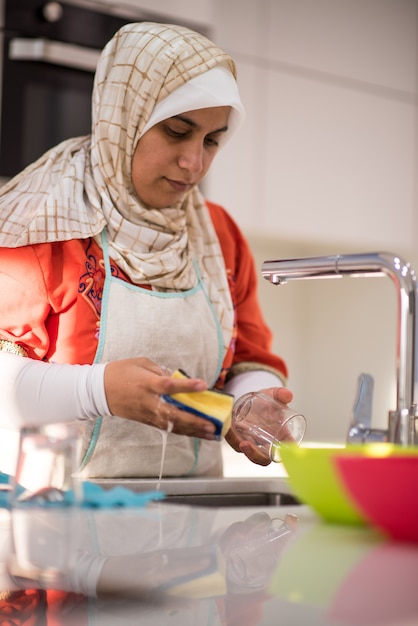 Moslim traditionele vrouw die in keuken schoonmaakt