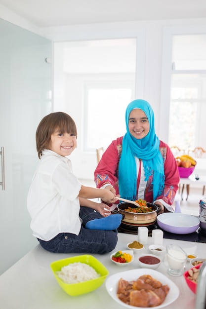 Moslim traditionele vrouw met weinig zoon in moderne witte keuken