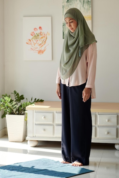 Moslim volwassen vrouw in hijab die thuis bidt
