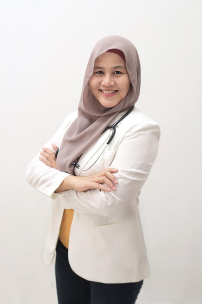 Moslim vrouwelijke arts die met gekruiste armen staat en een stethoscoop vasthoudt succesvolle zelfverzekerde persoon