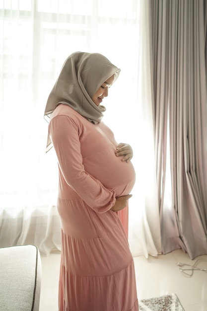 Moslim zwangere vrouw aziaat thuis kijken naar haar buik