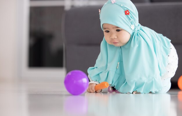 Moslimbaby speelt met kleurrijk speelgoed in de woonkamer.