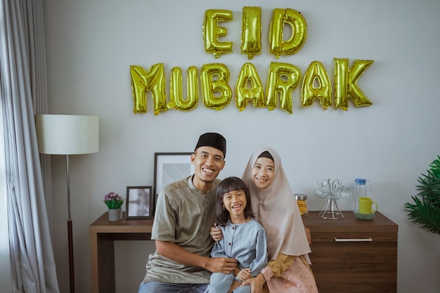 Moslimfamilie glimlacht terwijl ze voor eid Mubarak-decoratie zit