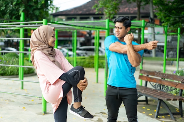 Moslimkoppels die staan te praten terwijl ze opwarmingsbewegingen maken voordat ze gaan trainen in het park