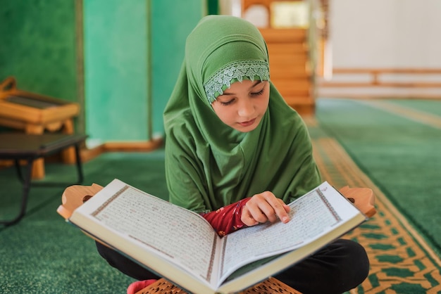 Moslimmeisje dat een heilig boek Koran leest in de moskee