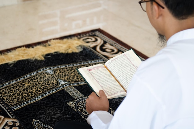 Moslimmens die heilige Koran lezen Heilige Koran in Hand met Arabische tekstbetekenis van Al Quran Islamitische conceptenachtergrond